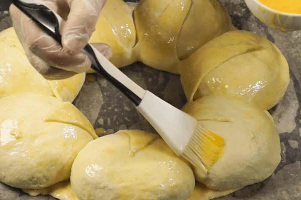 Загнуть «уголки» теста. Еще раз смазать яйцом.