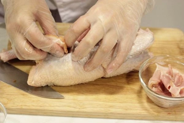 Сделать небольшие надрезы на тушке в грудке и бедрах. Нашпиговать нарезанными кусочками бекона.