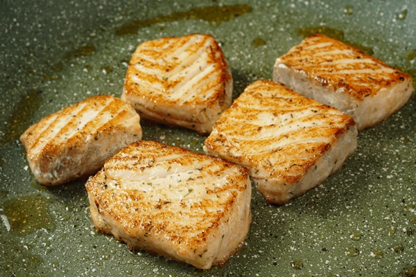 На другой сковороде обжарить кусочки рыбы до румяного цвета, примерно по 1,5 минуты с каждой стороны. Снять с огня в теплое место.