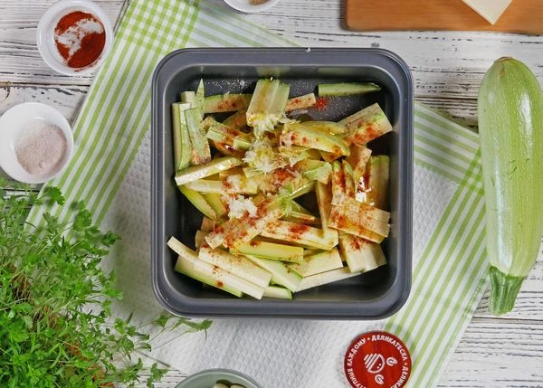 Кабачки выложить в форму для запекания. Посыпать паприкой, солью, чесноком и тертым пармезаном. Полить маслом, перемешать.