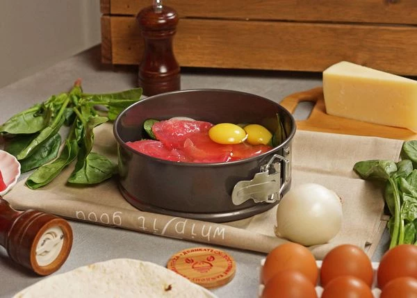 Сверху нарезанные слайсы тунца, посолить и поперчить. Добавить сырые яйца.