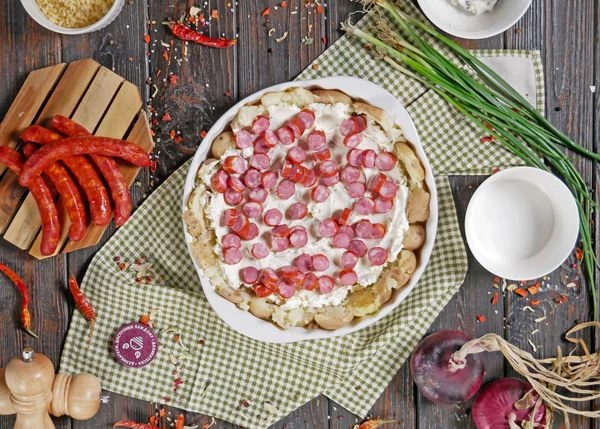 По картофелю распределить творожный сыр и нарезанные колбаски.