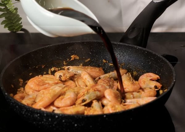 Нагрев сковороды снизить до среднего. Влить соевый соус, лимонный сок и рисовый уксус, добавить сахар и красный перец. Аккуратно перемешать. Жарить 1 минуту до карамелизации сахара и соевого соуса. 