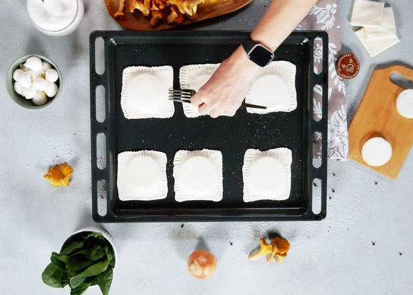 Накрыть лук кусочком теста. Примять края теста вилкой. Повторить со всеми кусочками теста и луком. Поставить в разогретую до 180 градусов духовку на 10 минут. 