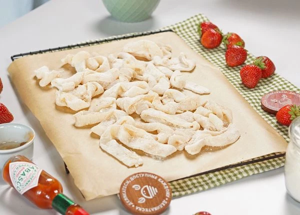 Подготовленные кальмары переложить на противень с пергаментом. Сбрызнуть маслом. Запекать в разогретой до 200 градусов духовке в течение 5 минут. 
