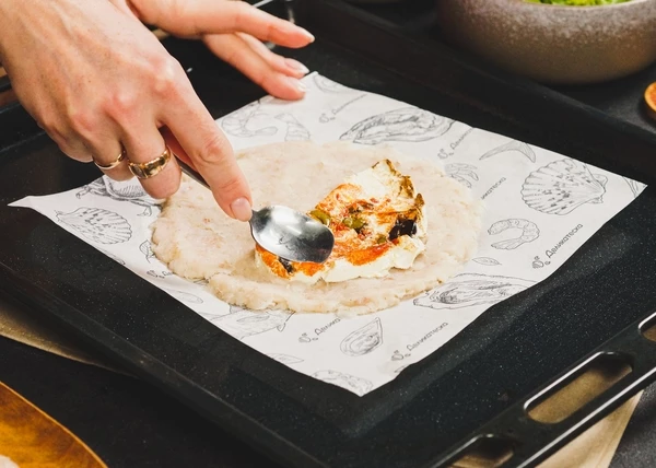 На пергамент выложить фарш, сформировать круг. На одну часть фарша  выложить ½ сыра.