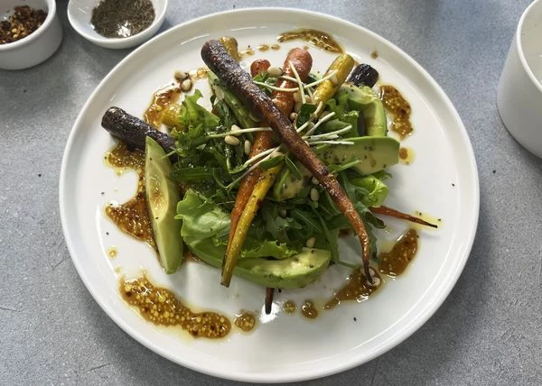 Авокадо вымыть, очистить, нарезать дольками. На тарелку для подачи выложить часть запеченной моркови, листья салата, рукколу, авокадо, микрозелень. Затем оставшуюся морковь. Полить заправкой. Посыпать орехами и семенами чиа. Приятного аппетита!
