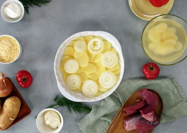 Лук очистить, нарезать тонкими кольцами. Выложить на картофель, посолить и поперчить. 