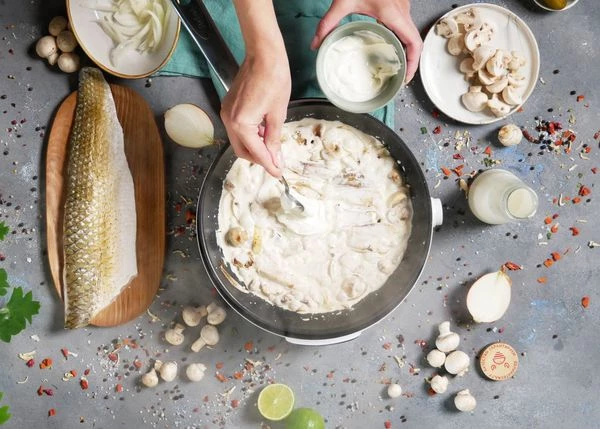 Влить сливки, довести до кипения, добавить сметану. Посолить, довести до кипения, снять с огня.