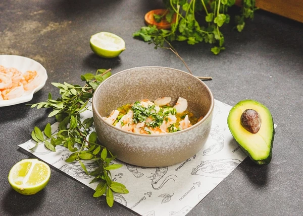 Креветки разморозить. Обжарить на оливковом масле в течение 2 минут, 4 креветки оставить на оформление, остальные нарезать. Авокадо вымыть, очистить, нарезать мелким кубиком. Добавить к маракуйе креветки, авокадо, нарезанную зелень, посолить. Перемешать.