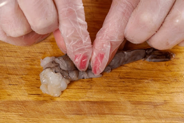 Затем креветки очистить от панциря, оставляя хвостик. По спинке продавить каждую креветку, чтобы во время жарки они не свернулись.