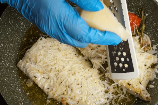 Готовую рыбу посыпать натертым сыром.