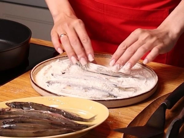 Мойву разморозить на нижней полке холодильника, промыть, просушить полотенцами и обвалять в муке со всех сторон. 