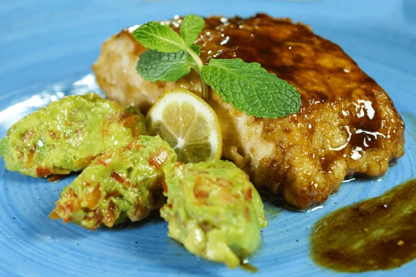 Готовую рыбу украсить зеленью, лимоном. Можно подать с соусом гуакамоле с красным перцем.