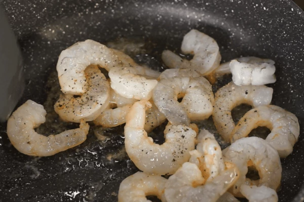 Креветки разморозить на нижней полке холодильника, обсушить на салфетке. В сковороду налить оливковое масло, обжарить креветки в течение 2 минут.