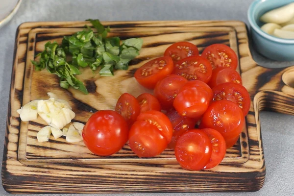 Томаты черри нарезать пополам. Базилик и чеснок мелко нарезать.