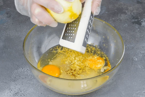 В глубокой чашке взбить сахар, яйца, растительное масло, ванильный экстракт и цедру лимона.