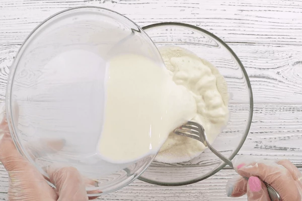 В глубокой чашке смешать сахар и просеянную муку (75 г), затем влить молоко, перемешать до однородного состояния, чтобы не было комочков.
