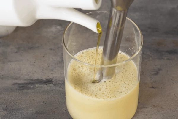 Тонкой струйкой влить оливковое масло, продолжая взбивать блендером. 