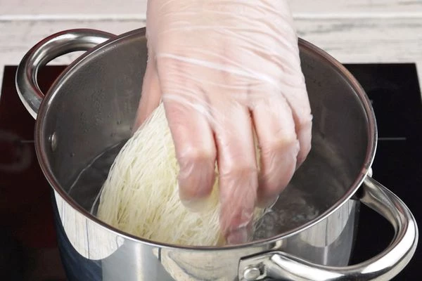 Рисовую лапшу заложить в кипяток, для пластичности лапши влить холодной воды, дать закипеть, затем снять с огня и дать ей доготовится в горячей воде, минут 5-6. Слить воду.