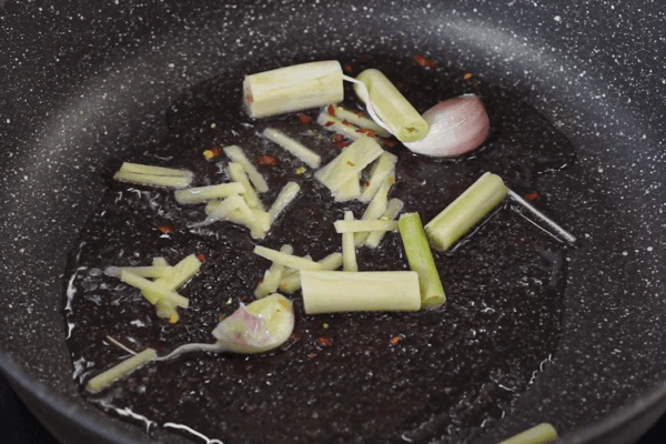 В сковороду выложить кокосовое масло, нагреть, добавить лемонграсс, чеснок, имбирь и перец чили, перемешать, прогреть пару минут.
