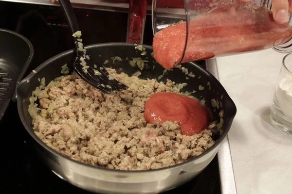 Влить протертый томат и специи. Тушить все до выкипания жидкости, примерно 15-20 минут на среднем огне. Влить вино, довести до кипения и снять с огня.