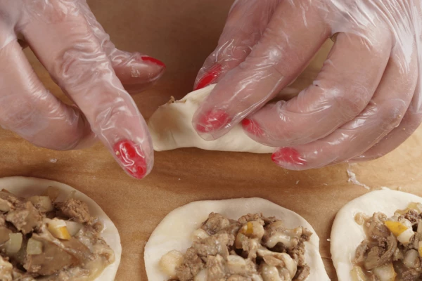 По центру круга выложить начинку, защипать в виде пирожков.