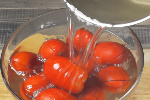 В глубокую жаропрочную чашку сложить помидоры, залить кипятком на 1-2 минуты.