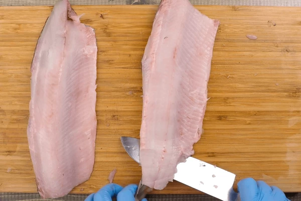  Разрезать на два филе вдоль хребта, удалить реберные кости, пинцетом вынуть мелкие спинные косточки. Затем снять кожу. 