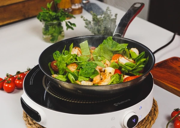 Затем добавить нарезанные томаты черри и шпинат, обжарить 1 минуту.