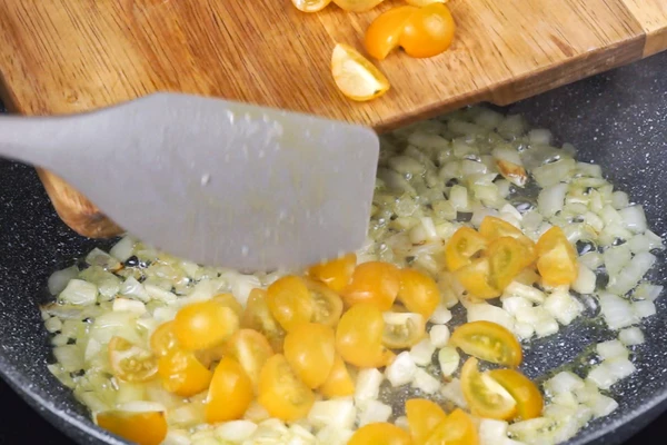 На разогретой с оливковым маслом сковороде обжарить до мягкости лук, посолить, добавить четвертинки черри, обжарить еще 2 минуты. Снять с огня.