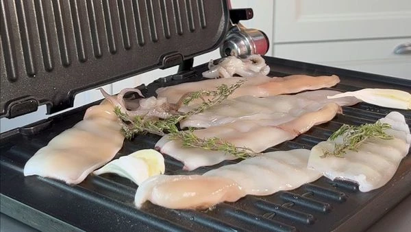 На гриль сковороде разогреть оливковое масло, добавить 2 зубчика раздавленного чеснока, обжарить кальмара до румяной корочки 1-2 минуты. Также на гриль сковороде обжарить сыр халуми в течение 2 минут.