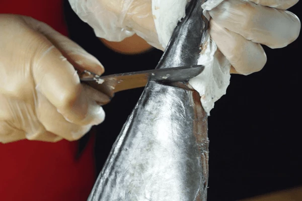 Держа за хвост срезать плавники.