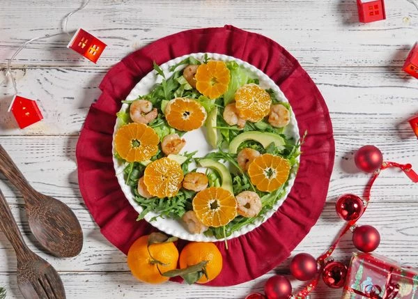 Мандарины очистить, нарезать кружочками. Выложить на листья салата.