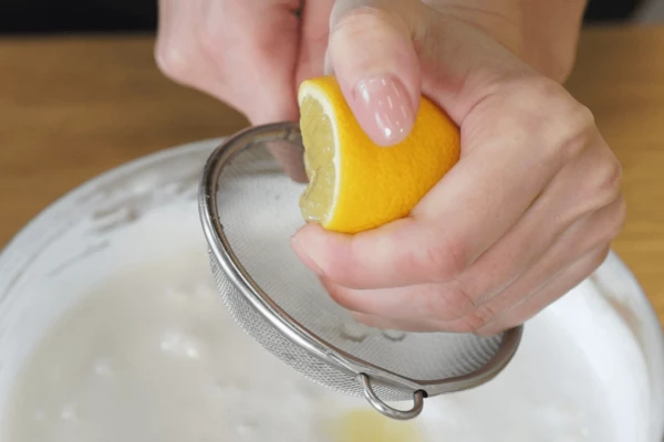 Лимон вымыть, нарезать пополам, выдавить процеженный сок, перемешать венчиком. Ввести крахмал, перемешать лопаткой.
