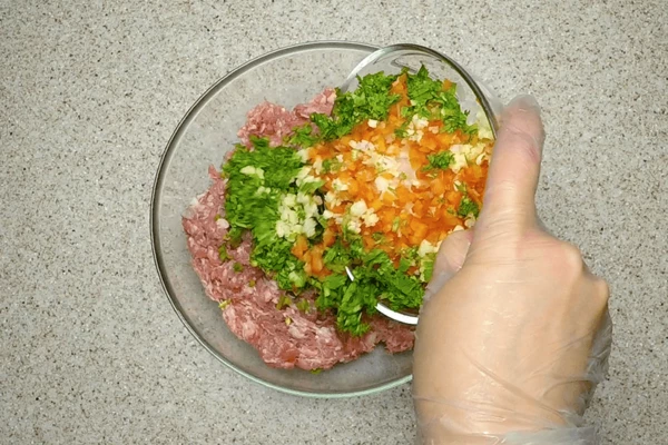 Добавить овощи в фарш, всыпать специи, посолить. 