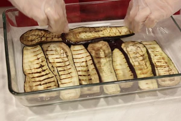 Подготовить форму для запекания с высокими бортами: первым слоем выложить половину баклажанов, затем половину фарша, затем снова баклажаны, фарш. Последний слой смазать густым соусом.