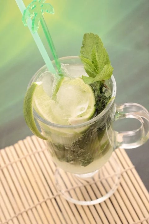 В бокал для коктейля положить лайм и мяту, хорошо размять. Влить сироп, добавить лед. Залить газированной водой.