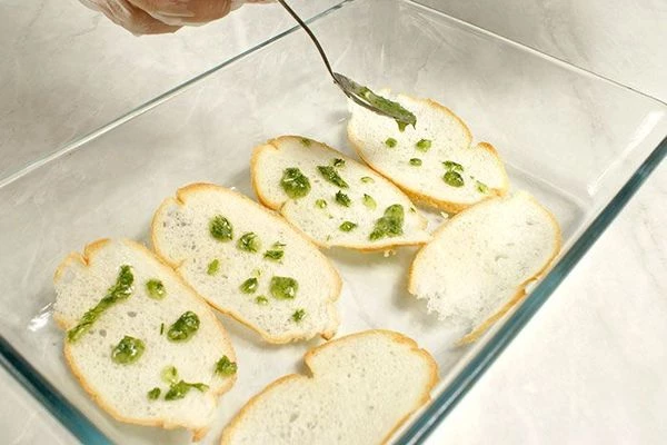 Тонкие пластики багета сбрызнуть зеленым маслом и подсушить в разогретой до 200С духовке  до золотистого цвета.