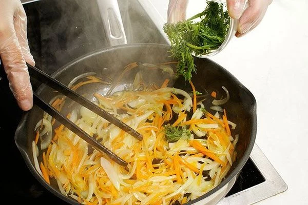 В обжаренные овощи добавить нарезанную зелень, поперчить по вкусу.