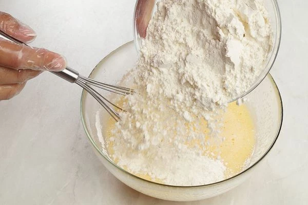 Затем к яичной смеси добавить просеянную муку и разрыхлитель.