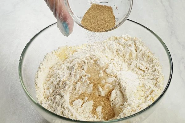 Добавьте к пшеничной муке семолину и дрожжи.