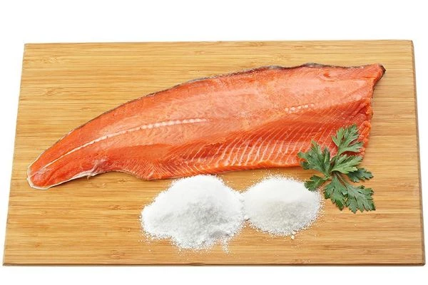 Рыбу разморозить на нижней полке холодильника. Разделать на филе. Филе обсыпать смесью сахара и соли, завернуть плотно в пергамент, затем убрать в холодильник на 5-6 часов. 