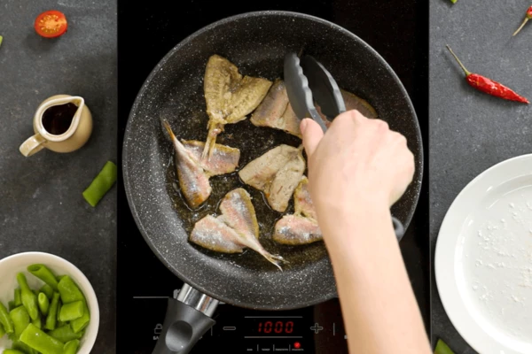 На сковороду налить половину масла, обжарить рыбу по 1 минуте с каждой стороны. 