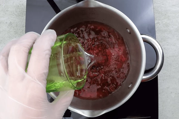 Для приготовления желе желатин (25 г) замочить в 50 г воды на 10-15 минут. В сотейник переложить протертую малину, добавить воду и набухший желатин.  Прогреть, не доводя до кипения. 