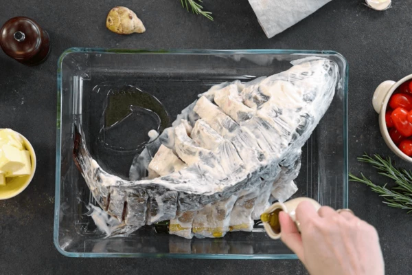 В форму для запекания выложить карпа, налить немного оливкового масла на свободное место.