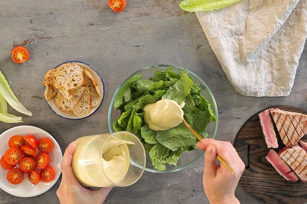 Томаты черри вымыть, разрезать пополам.
Листья салата вымыть, обсушить, порвать средними кусочками и перемешать с соусом. 
