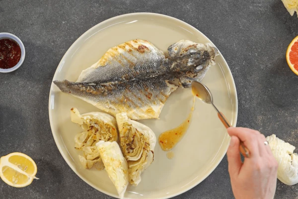 На тарелку для подачи выложить готовый сибас, айсберг. Айсберг полить соусом. Оформить долькой лимона.

