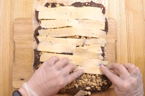 Сыр с помощью ножа для сыра или овощечистки нарезать тонкими пластиками. Разложить в один слой на орехи.