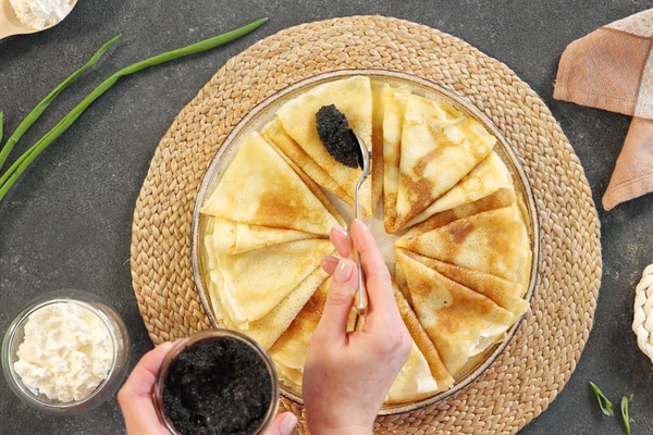 Блинчики выложить на тарелку для подачи. Оформить икрой, сыром рикотта и нарезанным луком.
